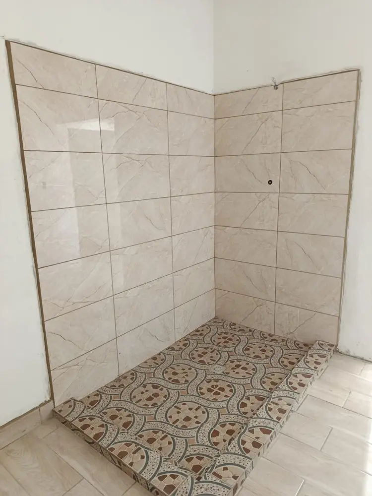 &Aacute;rea de ducha con azulejo tipo m&aacute;rmol en las paredes y piso de cer&aacute;mica decorada