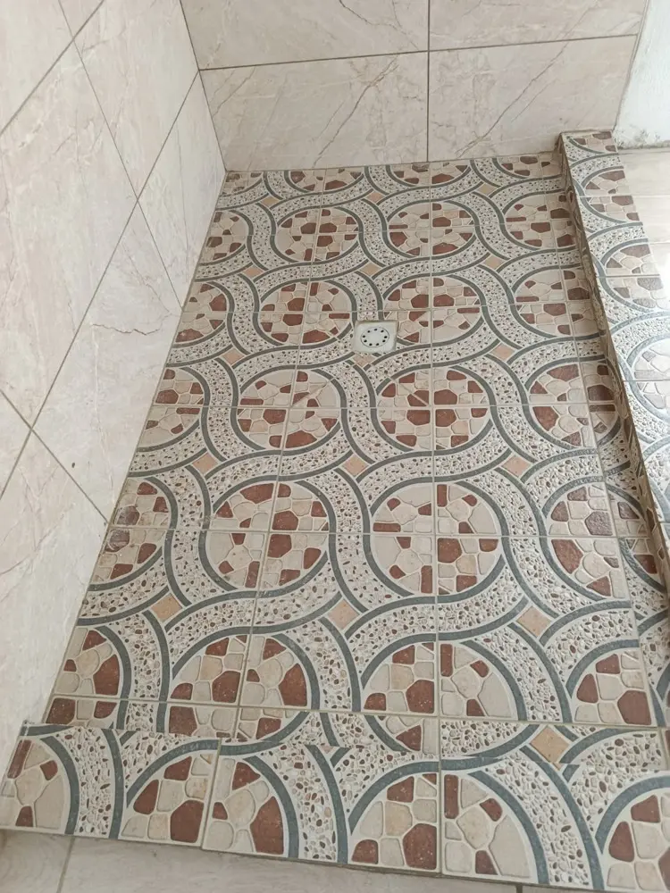 Piso de cer&aacute;mica decorada con drenaje al centro y patr&oacute;n alineado