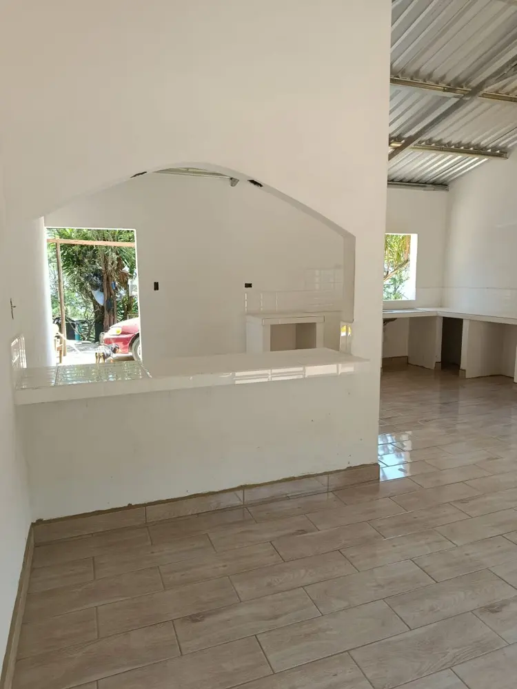 Sala terminada con paredes repelladas y pintadas en blanco, con barra de cocina en arco