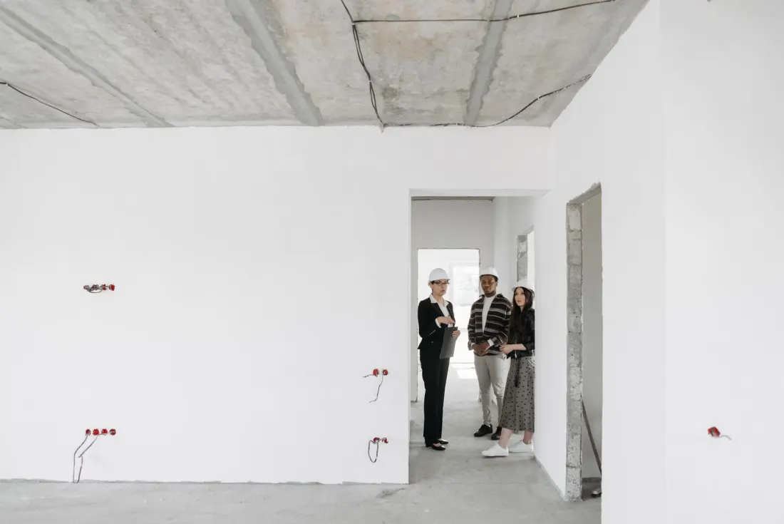 Una familia conversa con el constructor dentro de una vivienda en obra gris