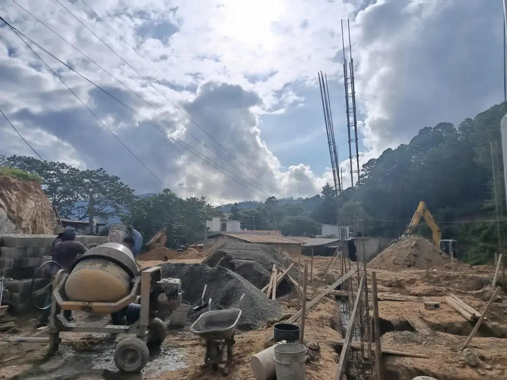 Excavaci&oacute;n de zanjas con retroexcavadora, concretera y columnas armadas asom&aacute;ndose sobre el terreno