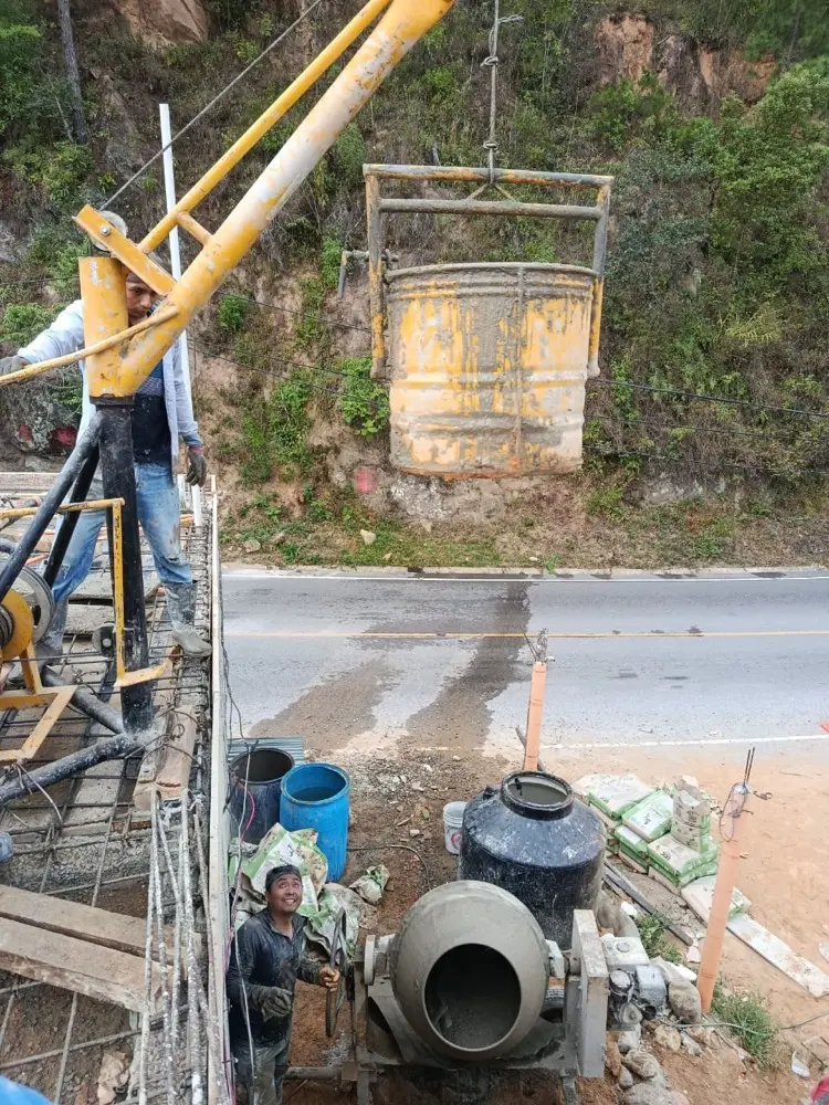 Pluma izando un bote de concreto durante la fundici&oacute;n de la losa, con la concretera abajo