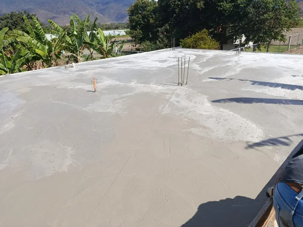 Losa de concreto reci&eacute;n fundida y alisada, con hierros de espera y vista a las monta&ntilde;as