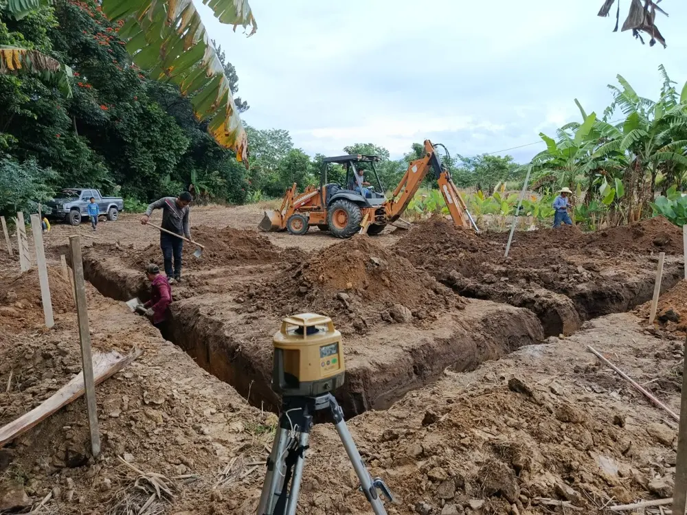 Excavaci&oacute;n de zanjas con retroexcavadora y nivel l&aacute;ser sobre el terreno trazado con estacas