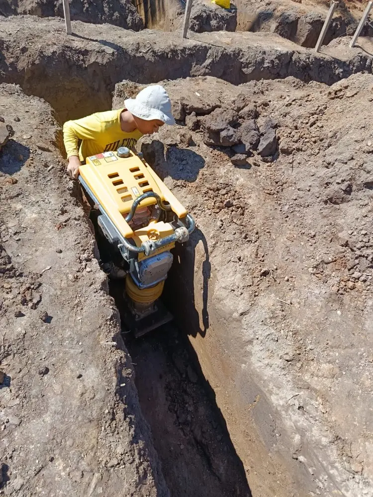 Trabajador compactando el fondo de una zanja con compactadora mec&aacute;nica