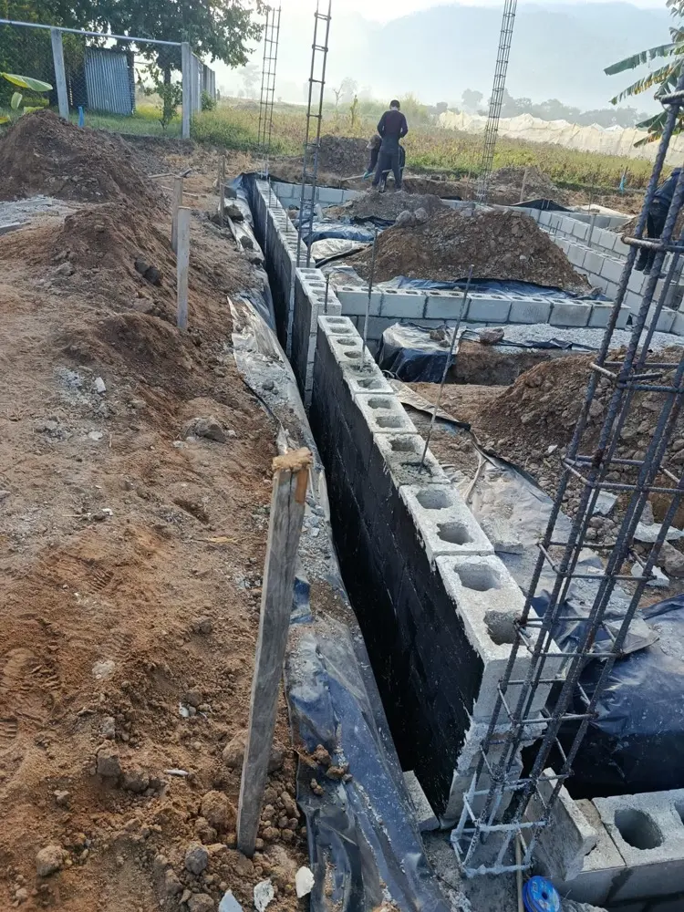 Cimiento de block cubierto con membrana impermeabilizante negra y armadur&iacute;a de columnas