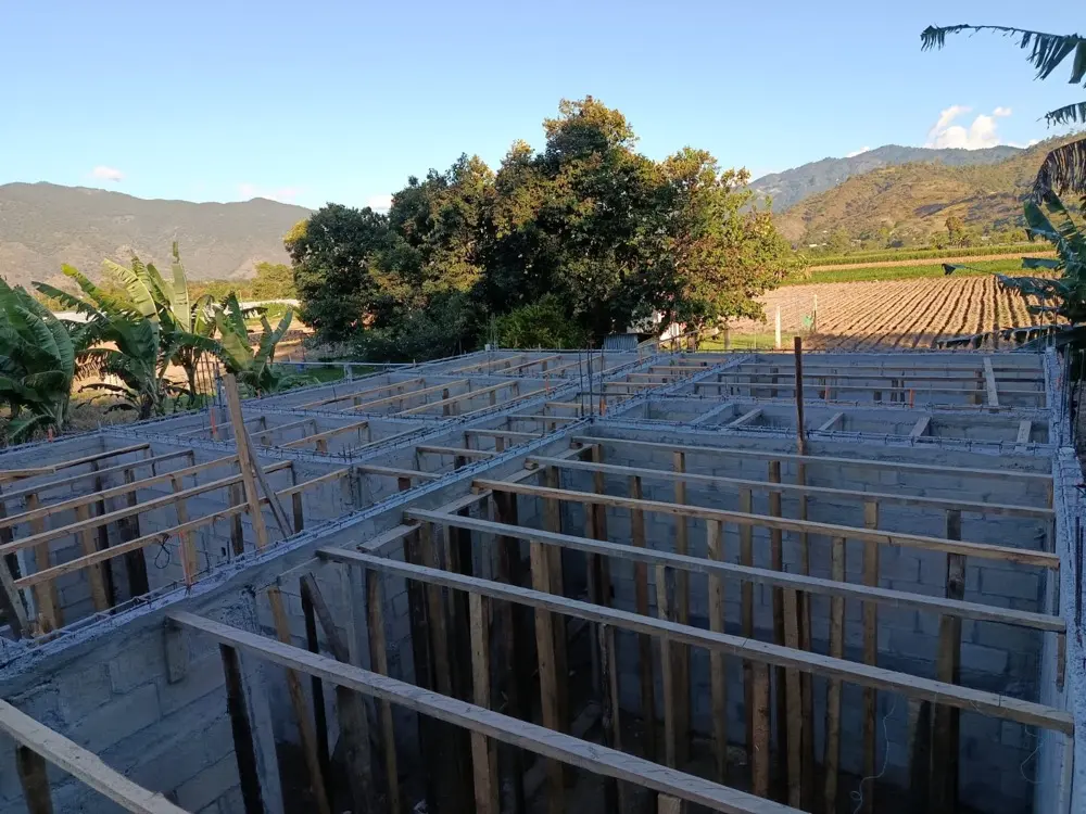 Vivienda en obra con el encofrado de la losa listo, con las monta&ntilde;as de Baja Verapaz al fondo