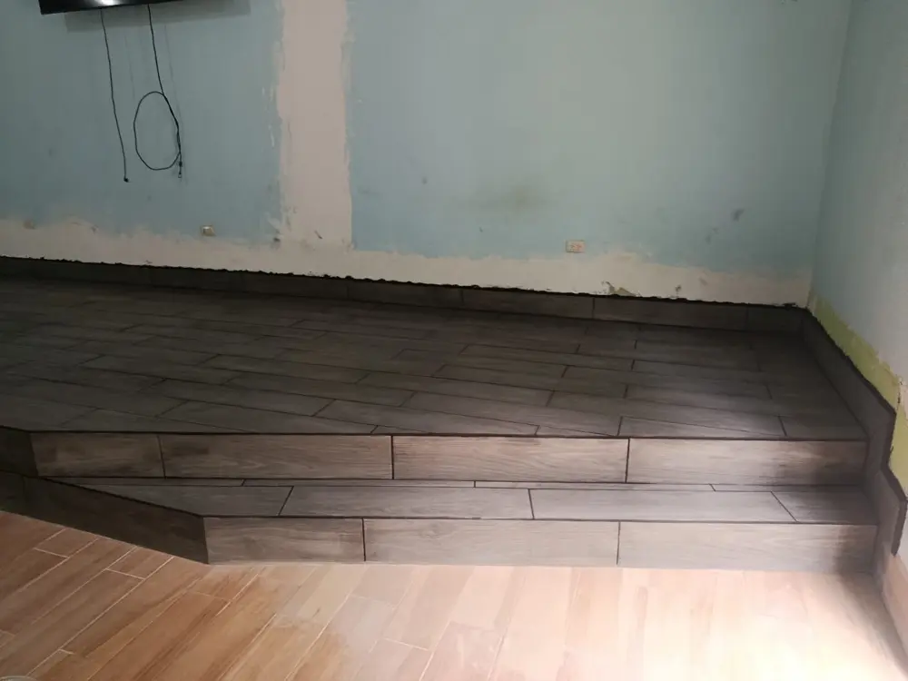 Plataforma de cer&aacute;mica gris con grada, junto al piso de cer&aacute;mica clara del sal&oacute;n